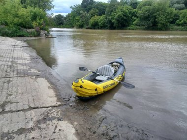 Toronto, ON, Kanada - 16 Ekim 2025: Sarı şişme bir kano Explorer çamurlu bir nehrin kenarında kürek ile pruva boyunca oturur..