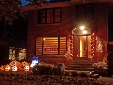 Toronto, ON, Kanada 31 Ekim 2024: Çimlerde ve balkonda parlayan Cadılar Bayramı şişme bebekleri, hayaletler, balkabakları ve ürkütücü bir ağaç...