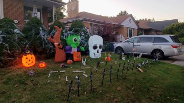 Toronto, ON, Kanada - 18 Ekim 2025: Bir iskan evinin ön bahçesinde Cadılar Bayramı 'nda şişme süslemeler ve iskeletler bulunur..