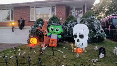 Toronto, ON, Kanada - 18 Ekim 2025: Bir iskan evinin ön bahçesinde Cadılar Bayramı 'nda şişme süslemeler ve iskeletler bulunur..