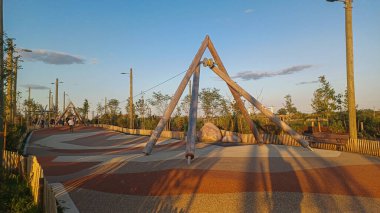 Toronto, ON, Kanada - 13 Ekim 2025: Toronto 'daki Biidaasige Park' ta ahşap yapıları olan bir şehir parkı ve insanlar renkli bir günbatımının keyfini çıkarıyorlar..