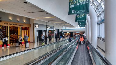 Toronto, ON, Kanada - 12 Ekim 2025: Yolcular geniş pencereli modern bir havaalanı terminali içinde hareket halindeki bir geçitte seyahat ediyorlar.