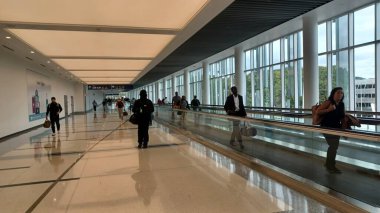 Charlotte, NC, ABD, 10 Ekim 2025: Bagajlı insanlar Charlotte Douglas Uluslararası Havalimanı 'nda parlak ve ferah bir salonda yürüyorlar