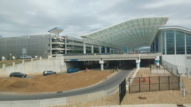 Charlotte, NC, ABD - 10 Ekim 2025: Araçlar, havalimanı terminali girişinin modern, eğri camlı cephesinin önünden geçerek,..