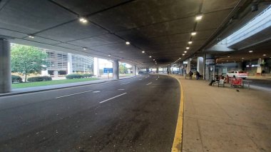 Toronto, ON, Kanada - 2 Ekim 2025: Büyük bir havaalanı terminalinin beton yapısının altındaki varış ya da çıkış yolu boyunca trafik ilerliyor.