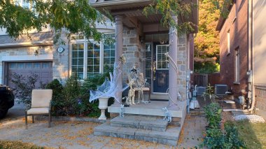 Toronto, Kanada - 12 Ekim 2025 Cadılar Bayramı için bir sundurma iskeletler, örümcek ağları ve şenlik sahnesi yaratan ürkütücü aksesuarlarla süslenmiştir..