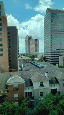 Dallas, TX, ABD - 3 Temmuz 2025 - Yüksek binalar mavi gökyüzü altında canlı bir şehir merkezinde alçak binaların üzerinde dimdik duruyorlar.