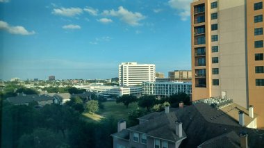 Dallas, TX, ABD - 3 Temmuz 2025 - Yüksek binalar mavi gökyüzü altında canlı bir şehir merkezinde alçak binaların üzerinde dimdik duruyorlar.