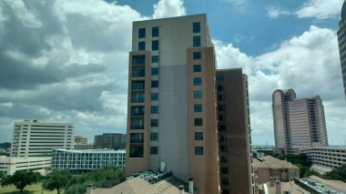 Dallas, TX, ABD - 3 Temmuz 2025 - Yüksek binalar mavi gökyüzü altında canlı bir şehir merkezinde alçak binaların üzerinde dimdik duruyorlar.