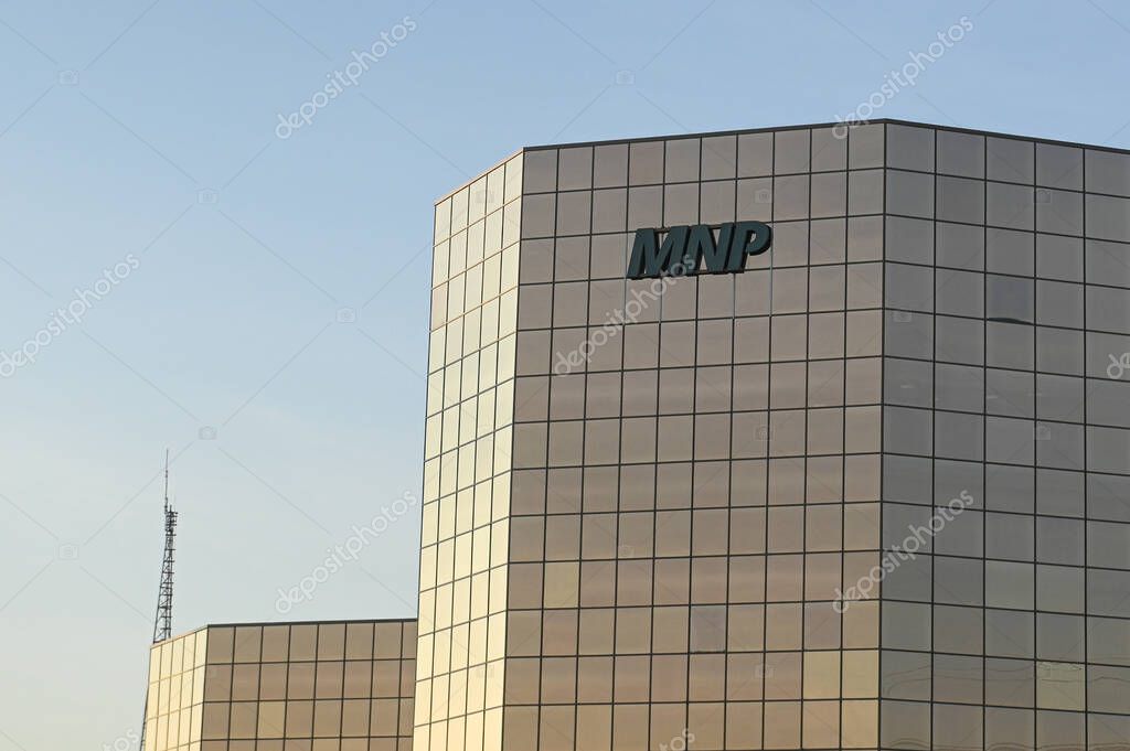 Calgary, AB, Canada - September 18, 2025: A sleek glass tower displays the MNP logo and Canadian flag against a clear blue sky.