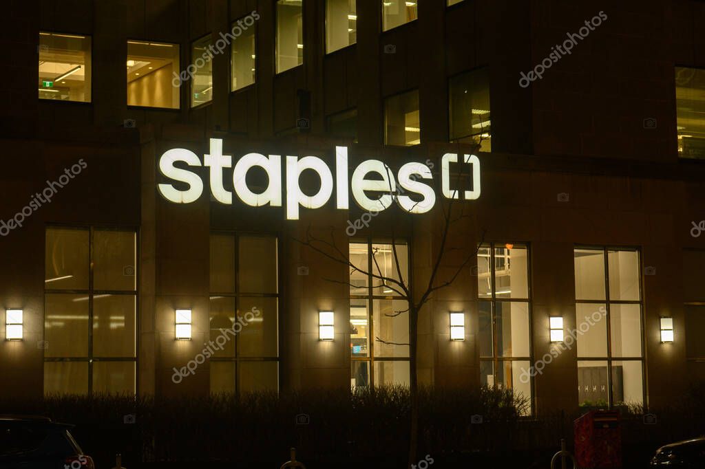 Toronto, ON, Canada - September 19, 2025: A Staples office supply store is lit up at night, with the illuminated logo visible on the side of the building.