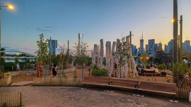 Toronto, ON, Kanada - 13 Ekim 2025: Toronto 'daki Biidaasige Park' ta ahşap yapıları olan bir şehir parkı ve insanlar renkli bir günbatımının keyfini çıkarıyorlar..