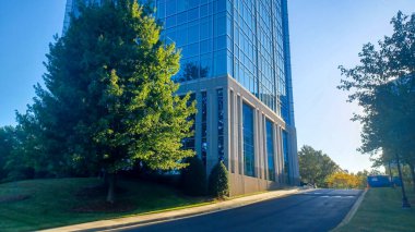 Charlotte, NC, ABD - 30 Eylül 2025: Modern ofis binaları yeşil çimenler, ağaçlar ve Ballantyne Corporate Park 'ta bir yürüyüş yolu arasında duruyor.