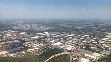 Dallas, TX, ABD - 15 Temmuz 2025: Güneşli, geniş bir hava manzarası büyük bir sanayi parkında sayısız beyaz çatılı depo ve ticari bina gösteriyor.