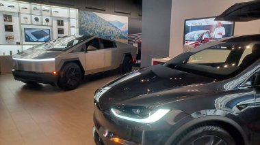 Toronto, ON, Kanada - 8 Kasım 2025: Kırmızı bir Tesla Model Y ve beyaz bir Tesla aracı büyük camlı ve kırmızı duvar aksanlı modern bir Tesla galerisinde sergilenmektedir.