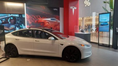 Toronto, ON, Kanada - 8 Kasım 2025: Kırmızı bir Tesla Model Y ve beyaz bir Tesla aracı büyük camlı ve kırmızı duvar aksanlı modern bir Tesla galerisinde sergilenmektedir.