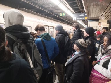 Toronto, ON, Kanada - 6 Kasım 2025: Banliyö treni kalabalık bir metro istasyonunda, kışlık giysiler giyerek ve kentsel ulaşım araçlarında çanta taşıyarak bekliyor.