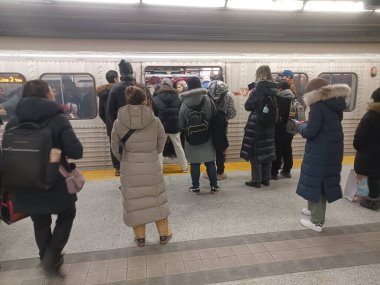 Toronto, ON, Kanada - 6 Kasım 2025: Banliyö treni kalabalık bir metro istasyonunda, kışlık giysiler giyerek ve kentsel ulaşım araçlarında çanta taşıyarak bekliyor.