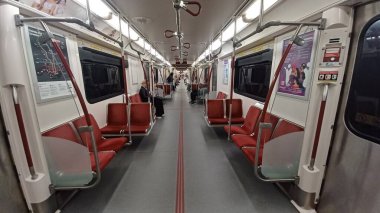 Toronto, ON, Kanada - 6 Eylül 2025: Modern bir metro vagonunun içi kırmızı koltuklar ve istasyonlar arasında seyahat eden birkaç yolcu gösteriyor.