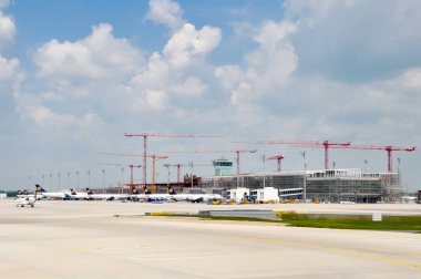 İstanbul, Türkiye - 9 Ağustos 2008: Münih Havalimanı 'ndaki Terminal 2 genişlemesi yeni inşaatı, birden fazla kule vincini ve pistteki Lufthansa uçaklarını gösteriyor