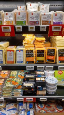 Toronto, ON, Kanada - 6 Aralık 2025: Bir süpermarkette peynir, yoğurt ve diğer dondurulmuş gıdalar dahil olmak üzere çeşitli süt ürünleri ile dolu uzun bir buzdolabı...