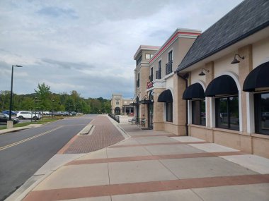 Charlotte, NC, ABD 29 Nisan 2025: Arabalı büyük bir otopark bulutlu bir gökyüzünün altında yol ve tuğla kaldırım kenarında oturuyor..