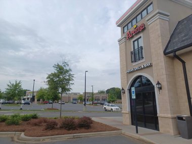 Charlotte, NC, ABD 29 Nisan 2025: Arabalı büyük bir otopark bulutlu bir gökyüzünün altında yol ve tuğla kaldırım kenarında oturuyor..