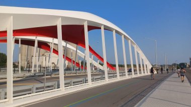 Toronto, ON, Kanada - 6 Temmuz 2025: Sarı kirişli modern bir kemerli köprü, açık ve güneşli bir günde yansımalı bir su kanalı boyunca uzanır.