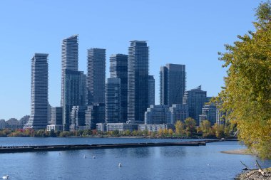 Ontario Gölü 'nün berrak mavi sularını kaplayan modern gökdelenler, sonbahar mevsiminde canlı bir şehir manzarası ve gelişimi sergiliyor.