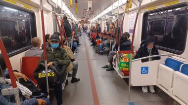 Toronto, ON, Kanada - 6 Eylül 2025: Modern bir metro vagonunun içi kırmızı koltuklar ve istasyonlar arasında seyahat eden birkaç yolcu gösteriyor.