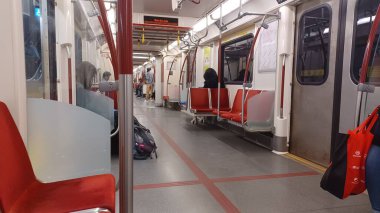 Toronto, ON, Kanada - 6 Eylül 2025: Modern bir metro vagonunun içi kırmızı koltuklar ve istasyonlar arasında seyahat eden birkaç yolcu gösteriyor.