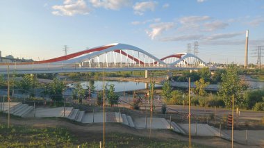 Toronto, ON, Kanada - 6 Temmuz 2025: Sarı kirişli modern bir kemerli köprü, açık ve güneşli bir günde yansımalı bir su kanalı boyunca uzanır.