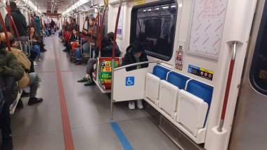 Toronto, ON, Kanada - 6 Eylül 2025: Modern bir metro vagonunun içi kırmızı koltuklar ve istasyonlar arasında seyahat eden birkaç yolcu gösteriyor.