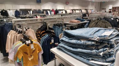 Toronto, ON, Kanada - 23 Kasım 2025: Modern bir perakende mağazasının içi müşterilerin bakmaları için raflarda ve raflarda çeşitli giyim ürünleri sergiliyor.