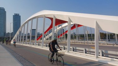 Toronto, ON, Kanada - 6 Temmuz 2025: Sarı kirişli modern bir kemerli köprü, açık ve güneşli bir günde yansımalı bir su kanalı boyunca uzanır.