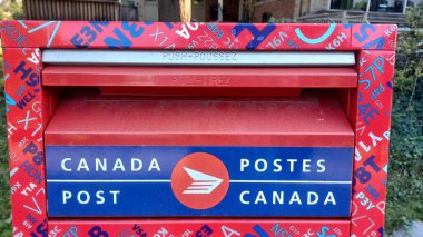 Toronto, ON, Kanada - 5 Ekim 2025: Kanada Posta Kutusunun kırmızı ve mavi tasarımı ve iki dilli Kanada Posta logosu