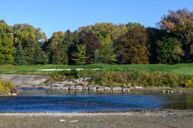 Humber Nehri, Toronto 'daki James Gardens' ta güneşli bir sonbahar gününde sonbahar renklerini gözler önüne sererek akar..
