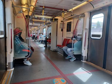 Toronto, ON, Kanada - 6 Eylül 2025: Modern bir metro vagonunun içi kırmızı koltuklar ve istasyonlar arasında seyahat eden birkaç yolcu gösteriyor.