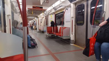 Toronto, ON, Kanada - 6 Eylül 2025: Modern bir metro vagonunun içi kırmızı koltuklar ve istasyonlar arasında seyahat eden birkaç yolcu gösteriyor.