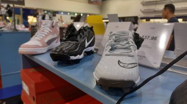 Toronto, ON, Kanada - 25 Eylül 2025: Bir perakende mağazasında sergilenen çeşitli spor ayakkabılarının altındaki raflarda çok sayıda kırmızı ve siyah ayakkabı kutusu düzenlidir.