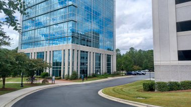 Charlotte, NC, ABD - 30 Eylül 2025: Modern ofis binaları yeşil çimenler, ağaçlar ve Ballantyne Corporate Park 'ta bir yürüyüş yolu arasında duruyor.