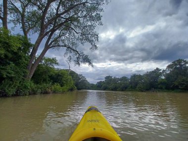Toronto, ON, Kanada - 19 Eylül 2025 Humber nehri yavaşça akar ve bulutlu bir günde sarı bir kano yavaşça suyun içinde hareket eder..
