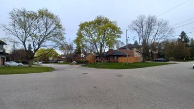 Toronto, ON, Kanada - 26 Nisan 2025: Görüntü, Etobicoke 'da sessiz bir yerleşim caddesini yakalıyor, baharın başlarında filizlenen ağaç ve evleri gösteriyor.