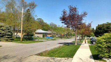 Toronto, ON, Kanada - 26 Nisan 2025: Görüntü, Etobicoke 'da yemyeşil ve çiçek açan ağaçların baharda vurgulandığı sakin bir yerleşim caddesine sahip..