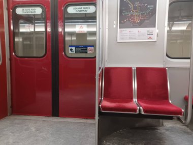 Toronto, ON, Kanada - 6 Eylül 2025: Modern bir metro vagonunun içi kırmızı koltuklar ve istasyonlar arasında seyahat eden birkaç yolcu gösteriyor.