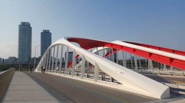 Toronto, ON, Kanada - 6 Temmuz 2025: Sarı kirişli modern bir kemerli köprü, açık ve güneşli bir günde yansımalı bir su kanalı boyunca uzanır.