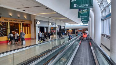 Toronto, ON, Kanada - 12 Ekim 2025: Yolcular geniş pencereli modern bir havaalanı terminali içinde hareket halindeki bir geçitte seyahat ediyorlar.