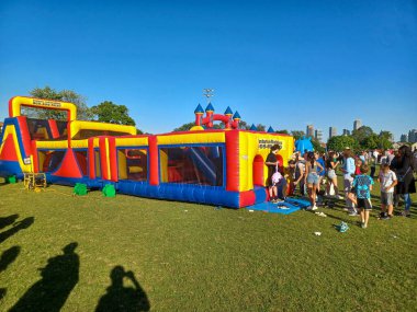 Toronto, ON, Kanada 31 Mayıs 2024: Aileler güneşli bir öğleden sonra bir çocuk etkinliğinde büyük şişme slaytlar ve engelli parkurların etrafında toplandılar..