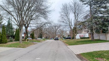 Toronto, ON, Kanada - 9 Nisan 2025: Park halindeki arabaların ve olgun ağaçların tomurcuklanmaya başladığı sakin bir yerleşim yeri..