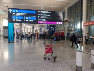 Toronto, ON, Kanada - 23 Ekim 2025: Bu sahne, yön işareti ve gezginlerle dolu bir havaalanı terminalindeki hareketleri resmediyor.